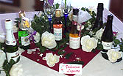 Mini wine and champagne bottles surrounded by roses on a tablecloth